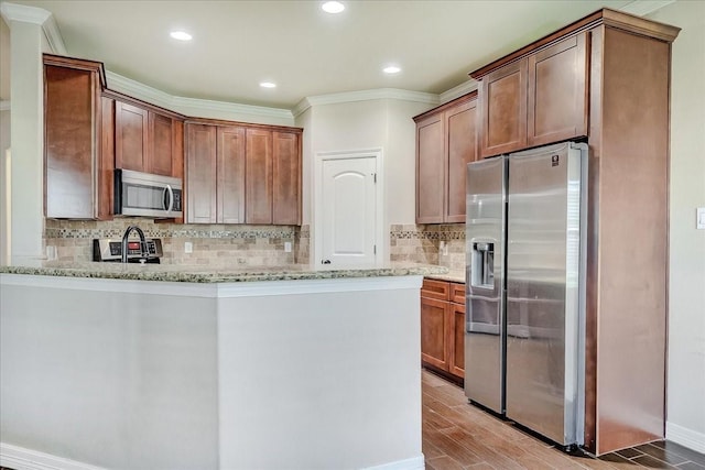 kitchen featuring light stone counters, kitchen peninsula, crown molding, and appliances with stainless steel finishes