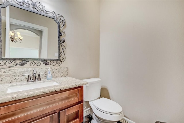 bathroom featuring vanity, an inviting chandelier, and toilet