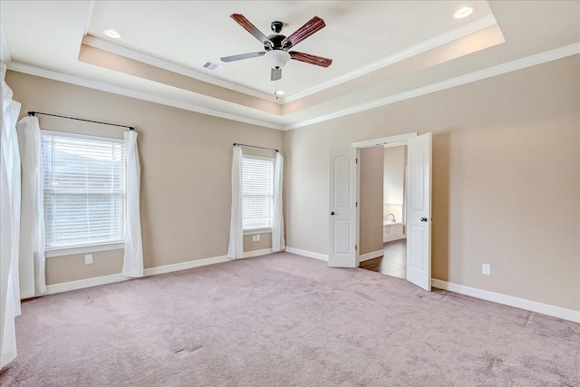 empty room featuring a raised ceiling, a wealth of natural light, and ornamental molding