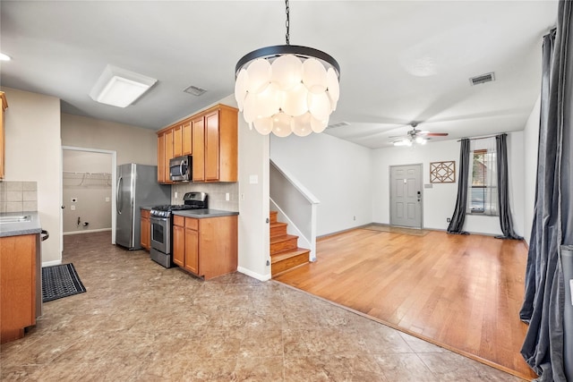 kitchen with stainless steel appliances, pendant lighting, light hardwood / wood-style floors, decorative backsplash, and ceiling fan with notable chandelier