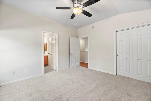 unfurnished bedroom featuring ceiling fan, ensuite bathroom, lofted ceiling, light carpet, and a closet