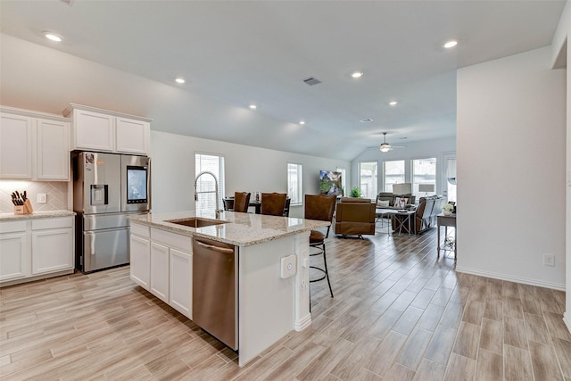 kitchen with white cabinets, stainless steel appliances, a kitchen island with sink, and sink