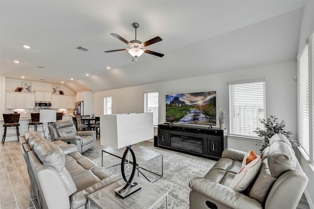 living room featuring ceiling fan, lofted ceiling, and light wood-type flooring