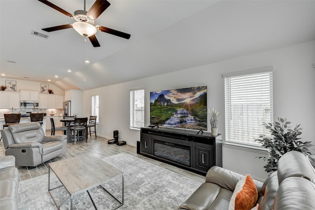 living room featuring a wealth of natural light, ceiling fan, and vaulted ceiling