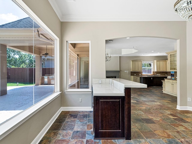 kitchen with crown molding, cream cabinets, a kitchen island, and a chandelier