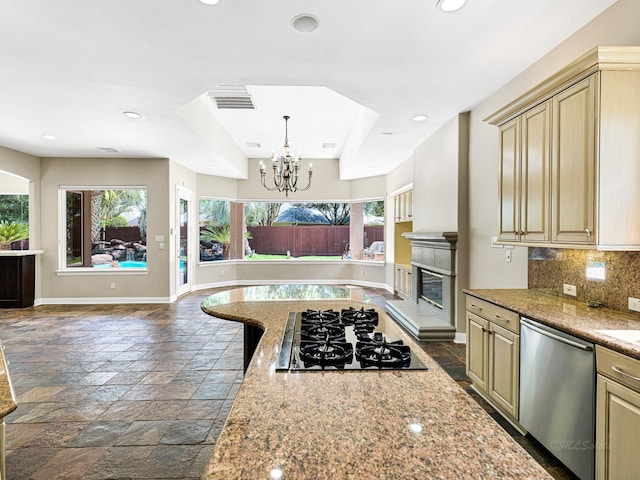 kitchen featuring light stone countertops, tasteful backsplash, gas stovetop, an inviting chandelier, and dishwasher