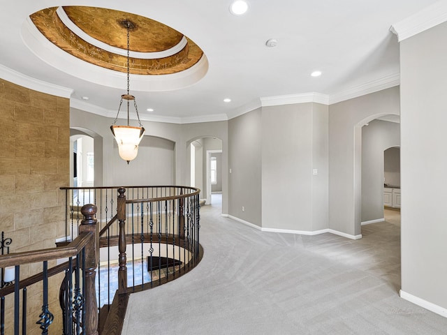 hall with carpet flooring, crown molding, and a tray ceiling