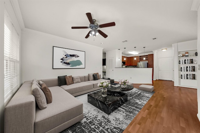 living room featuring wood-type flooring, ceiling fan, and crown molding