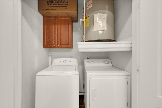 clothes washing area with cabinets, electric water heater, and washer and clothes dryer