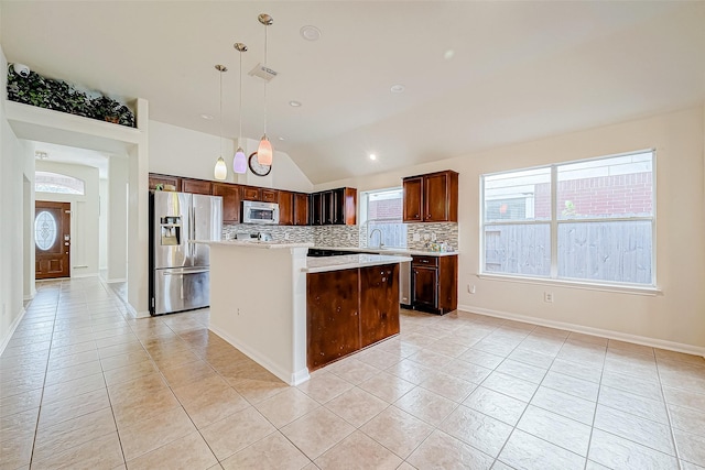 kitchen featuring pendant lighting, a center island, lofted ceiling, decorative backsplash, and stainless steel appliances