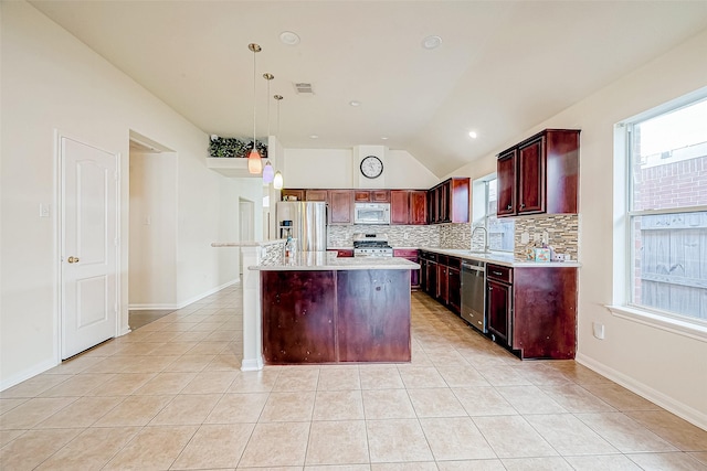 kitchen with appliances with stainless steel finishes, decorative light fixtures, a center island, lofted ceiling, and light tile patterned flooring