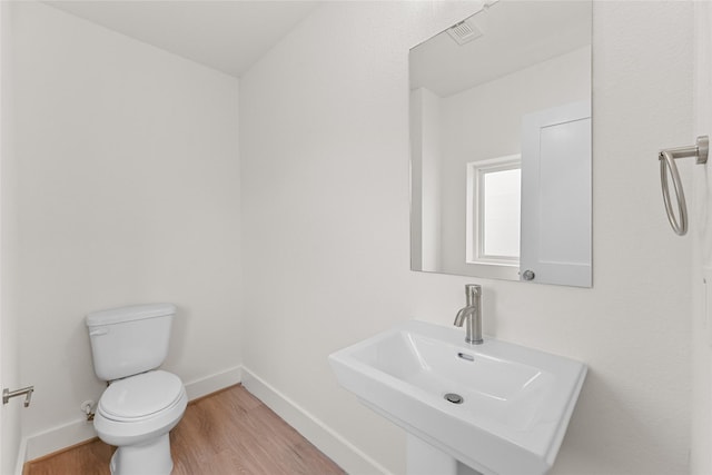 bathroom with wood-type flooring, toilet, and sink