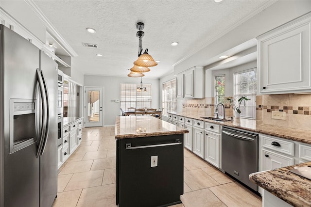 kitchen featuring white cabinetry, a center island, sink, stainless steel appliances, and pendant lighting