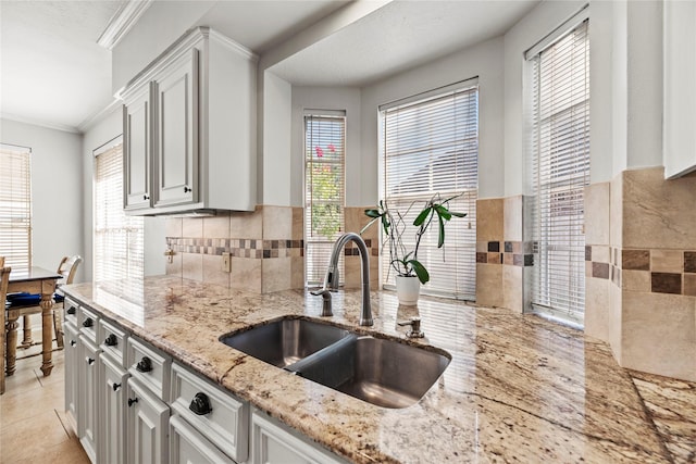 kitchen with light tile patterned floors, white cabinetry, sink, and a wealth of natural light