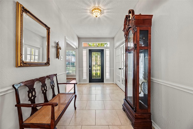 foyer with french doors, light tile patterned floors, and a textured ceiling