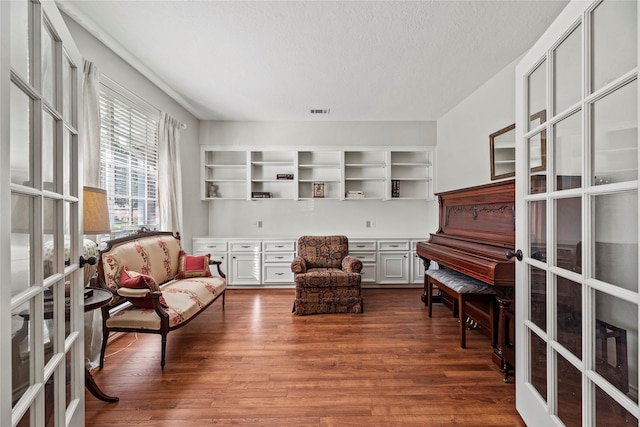 sitting room with french doors, dark hardwood / wood-style flooring, and a textured ceiling