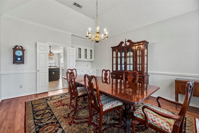 dining space with a notable chandelier, wood-type flooring, and ornamental molding