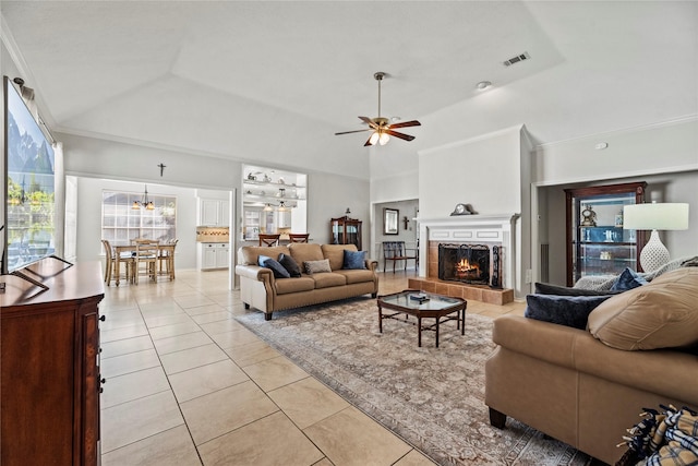 living room with ceiling fan, vaulted ceiling, a tray ceiling, light tile patterned flooring, and ornamental molding