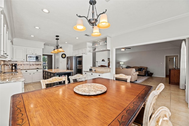 tiled dining area with ceiling fan with notable chandelier, ornamental molding, and sink