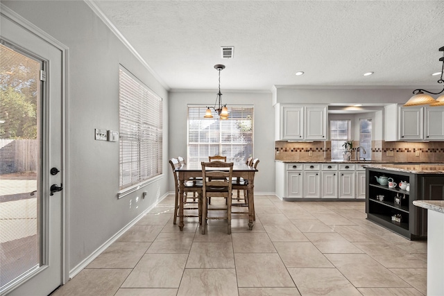 dining room featuring a notable chandelier, ornamental molding, a textured ceiling, and light tile patterned floors