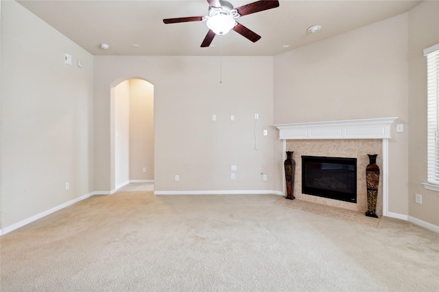 unfurnished living room with ceiling fan, a fireplace, and light colored carpet