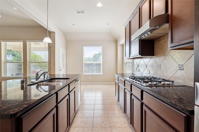 kitchen with an island with sink, sink, light tile patterned floors, and dark stone counters