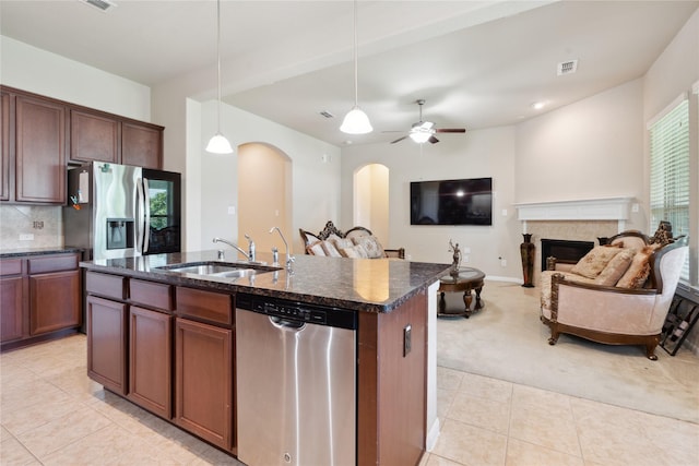 kitchen featuring stainless steel appliances, ceiling fan, sink, pendant lighting, and an island with sink