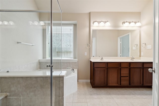 bathroom with tile patterned floors, tiled bath, a wealth of natural light, and vanity