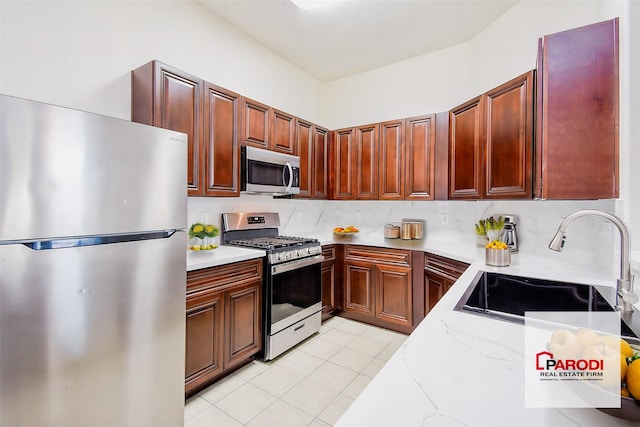 kitchen with light stone countertops, sink, stainless steel appliances, and light tile patterned flooring