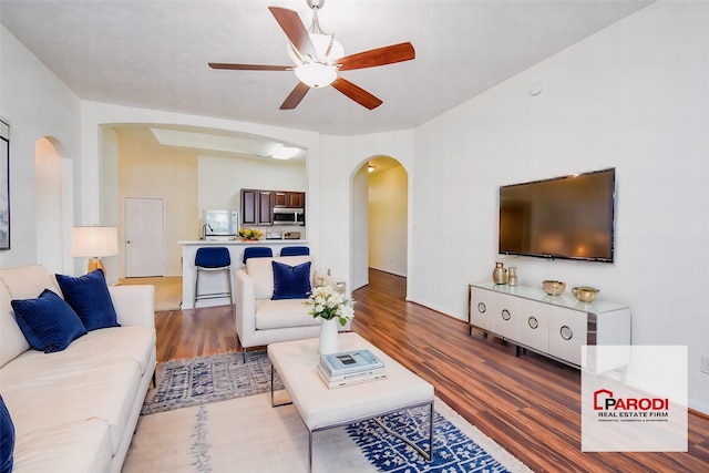 living room with ceiling fan, wood-type flooring, and sink