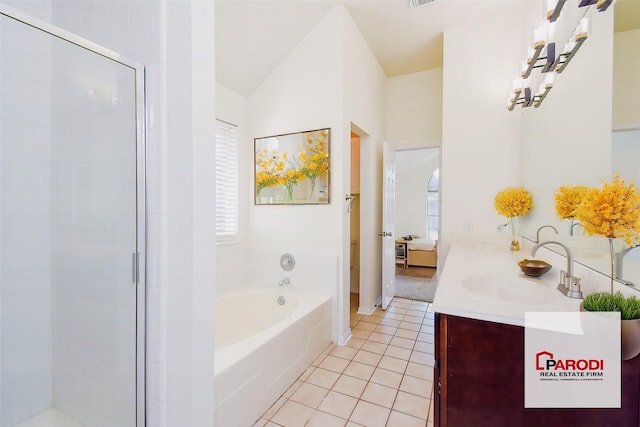 bathroom with tile patterned floors, lofted ceiling, a tub to relax in, and vanity