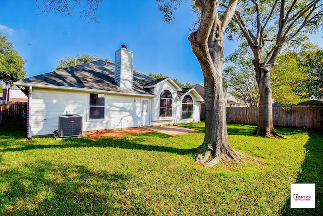 back of house with central AC unit and a yard