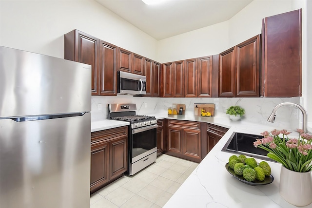 kitchen with light tile patterned floors, decorative backsplash, light stone countertops, and appliances with stainless steel finishes