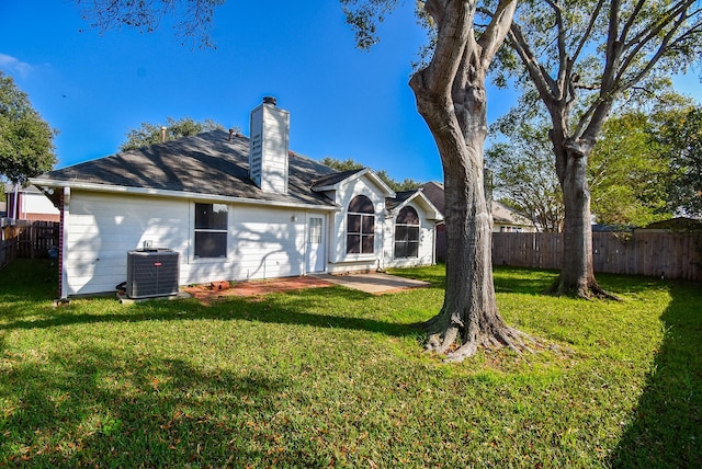 rear view of property with cooling unit and a lawn