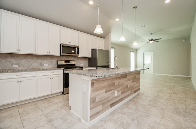 kitchen featuring stainless steel appliances, vaulted ceiling, ceiling fan, white cabinetry, and an island with sink