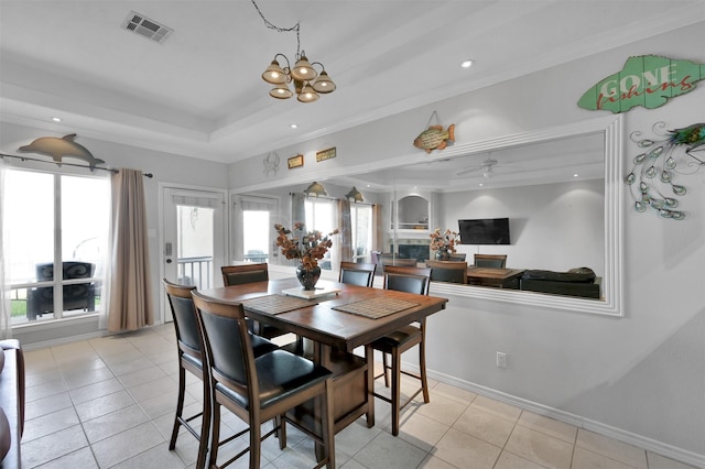 tiled dining area with a raised ceiling, crown molding, and ceiling fan with notable chandelier