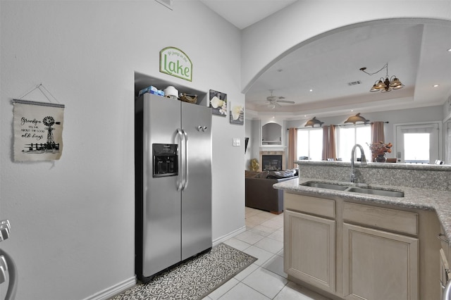 kitchen with a tray ceiling, ceiling fan, sink, stainless steel fridge with ice dispenser, and light tile patterned flooring