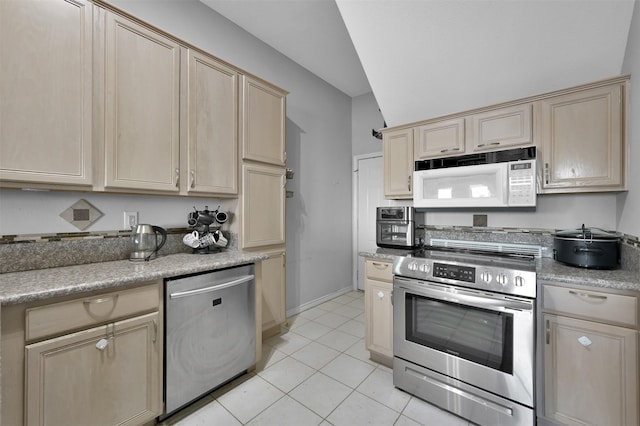 kitchen featuring light brown cabinetry, light tile patterned floors, vaulted ceiling, and appliances with stainless steel finishes