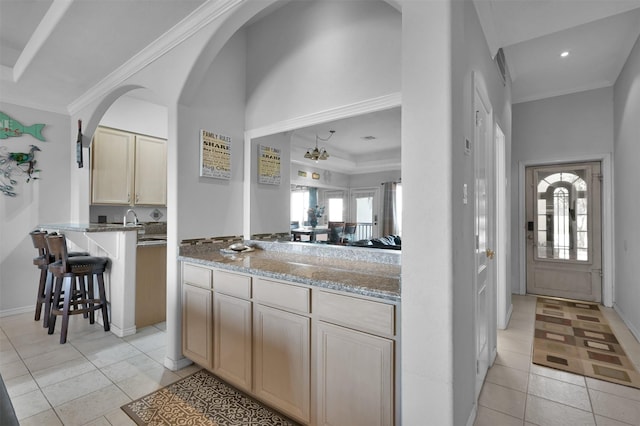 kitchen featuring light tile patterned floors, light stone counters, a healthy amount of sunlight, and a breakfast bar area