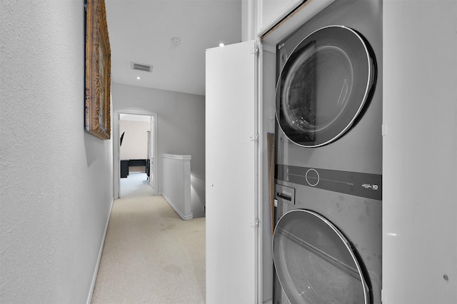 laundry area featuring light carpet and stacked washer / drying machine