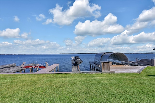 view of dock with a yard and a water view