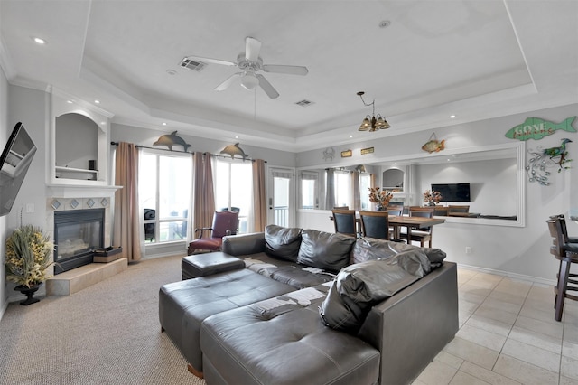 tiled living room featuring a tray ceiling, a tile fireplace, and ceiling fan