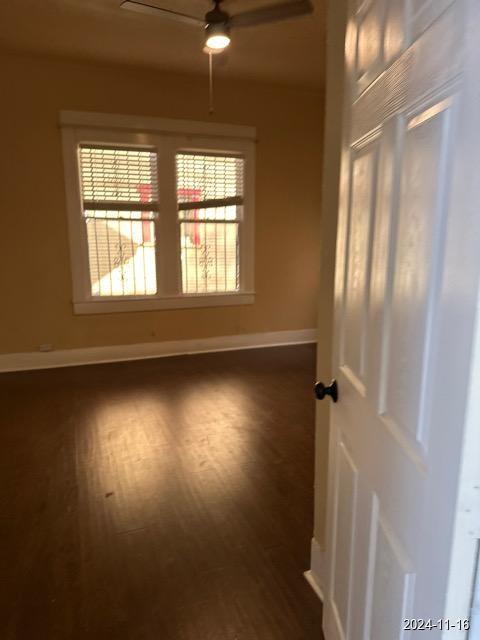 empty room featuring ceiling fan and dark wood-type flooring