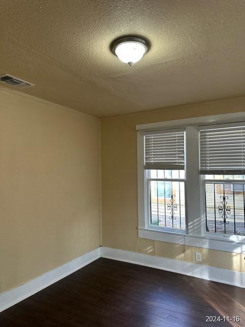 empty room featuring dark hardwood / wood-style floors and a textured ceiling