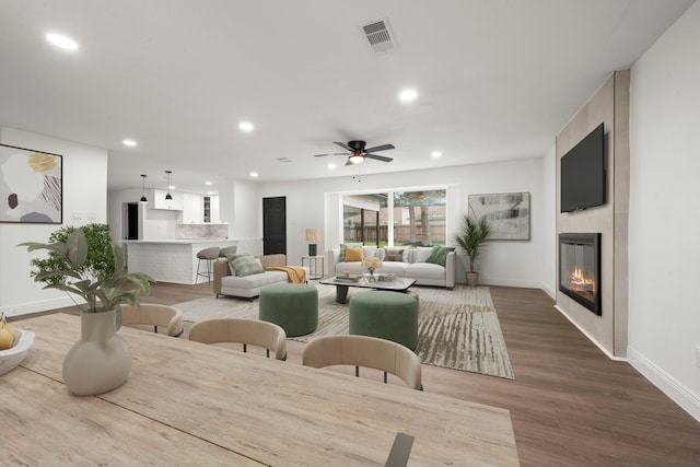 dining area featuring ceiling fan, light hardwood / wood-style floors, and a fireplace