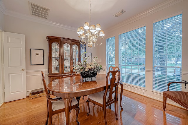 dining area with crown molding, a healthy amount of sunlight, light wood-type flooring, and an inviting chandelier