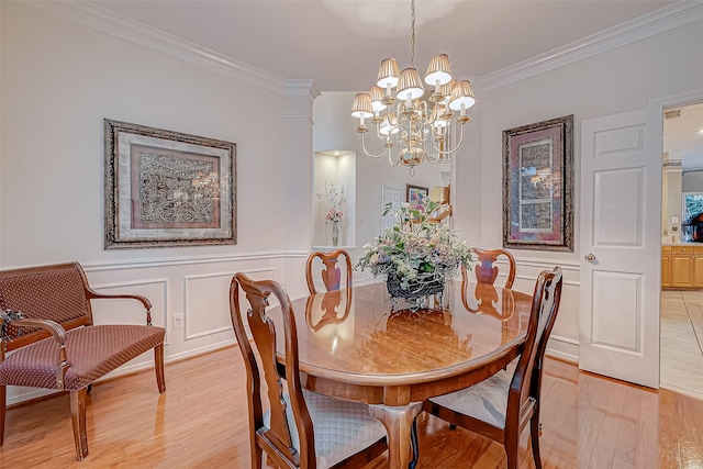 dining room featuring ornamental molding, light hardwood / wood-style flooring, and an inviting chandelier