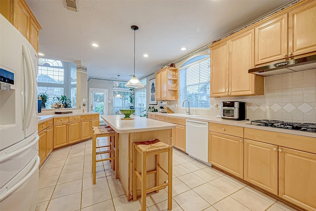 kitchen featuring a kitchen island, a kitchen breakfast bar, pendant lighting, white appliances, and light tile patterned floors