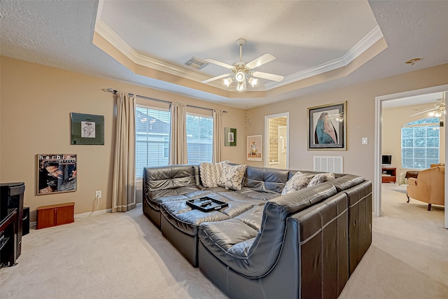 living room featuring light carpet, a tray ceiling, and ceiling fan