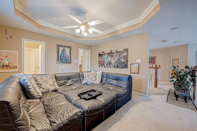 bedroom featuring ensuite bath, ceiling fan, a raised ceiling, crown molding, and light colored carpet